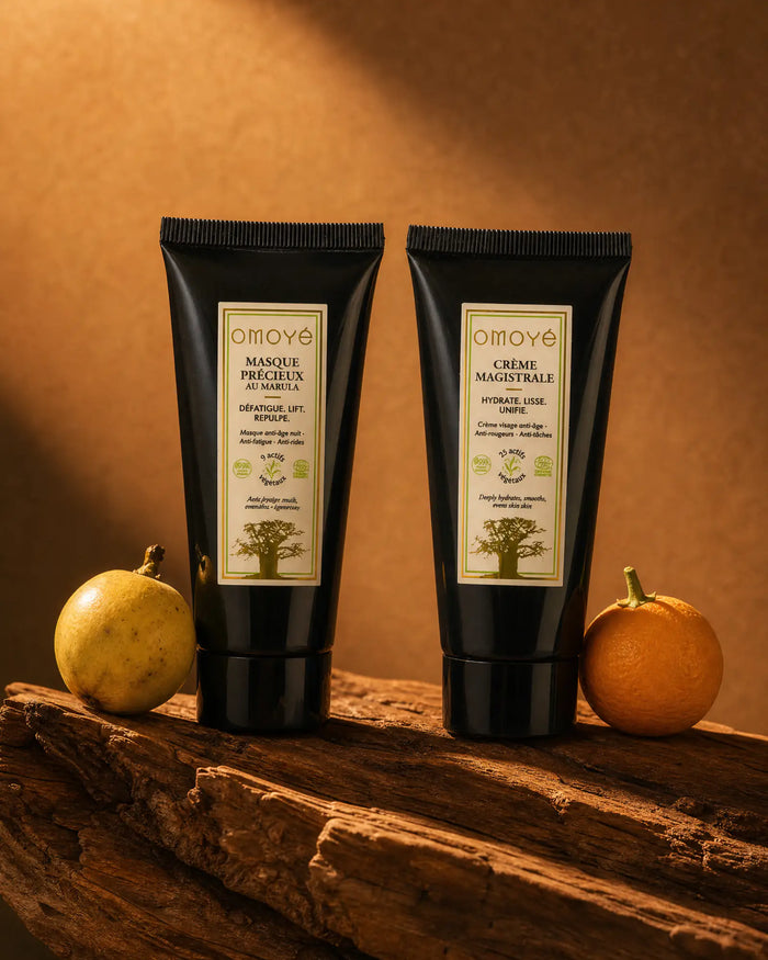 Masque Précieux au Marula et Crème Magistrale sur un bois flotté, entre un fruit de marula et une bigarade, fond terracotta